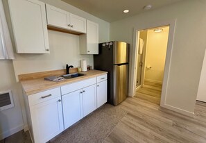 A modern kitchen with white cabinets, a stainless steel refrigerator, and a wooden countertop. - Woodside Retreat Estate - Home + Guest Barn (Bend)