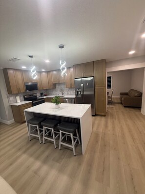 A modern kitchen with a central island, stainless steel appliances, and wooden cabinets. - 3-bedroom 2 bath house in serene Tampa 4 min drive from airport (Tampa)