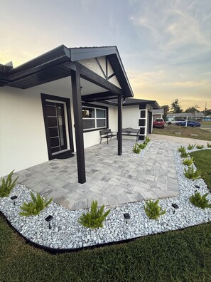 A modern house with a covered patio, a garage, and a driveway. - 3-bedroom 2 bath house in serene Tampa 4 min drive from airport (Tampa)