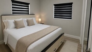 Una camera da letto con un letto, comodini, un lampadario a soffitto e due finestre con persiane.
