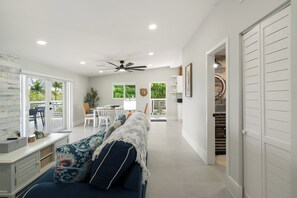 A spacious living area with a ceiling fan, a dining table with chairs, and a view of the outdoors through large windows. - Islamorada Waterfront Retreat Private Beach, Boat Lift & Canal Access (Islamorada)