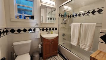 A bathroom with a toilet, sink, mirror, and shower.