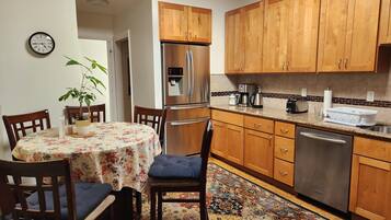 A compact kitchen with wooden cabinets, a stainless steel refrigerator, a coffee maker, and a dishwasher.