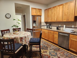 A compact kitchen with wooden cabinets, a stainless steel refrigerator, a coffee maker, and a dishwasher. - Sunny, Spacious 3-bedroom apartment in Vibrant Mission District of San Francisco (San Francisco)