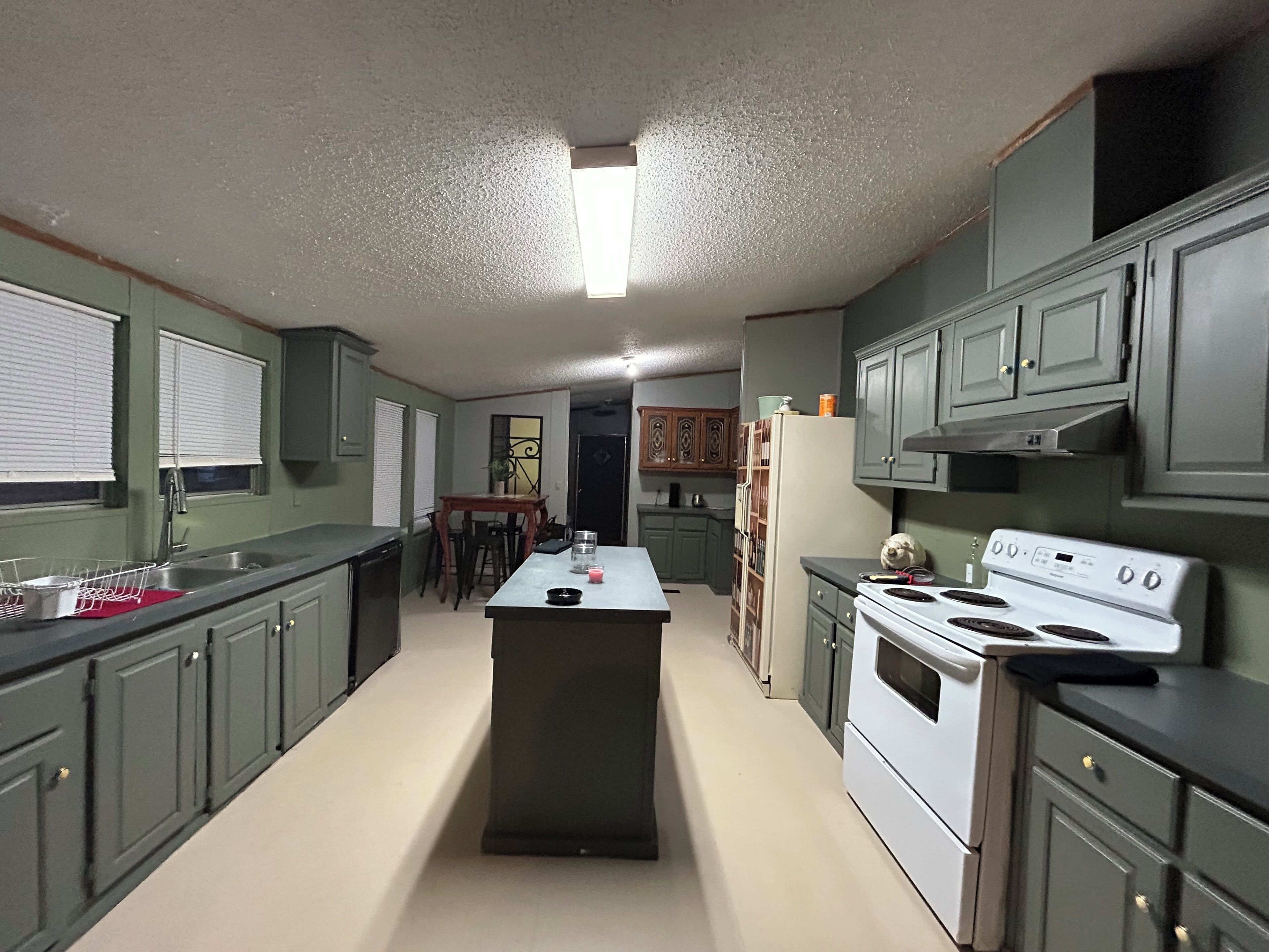 A kitchen with a central island, a stove, and a refrigerator.