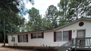 A mobile home with a front porch, a small staircase, and a window with shutters. - Adorable 3-bedroom  home great for fishing on a private lake in Central Georgia (Macon)