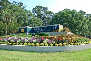 Schild für Palmetto Dunes Oceanfront Resort, umgeben von einem angelegten Garten.