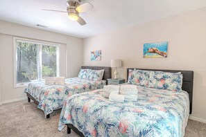 A bedroom with two beds, a ceiling fan, a window with blinds, and artwork on the walls. - Steps to Beach | Palmetto Dunes Pool & Hot Tub (Hilton Head Island)