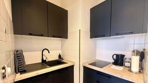 A compact kitchen with black cabinets, a sink, a countertop, and a coffee maker. - A052 Cosy studio near Croisette and the beach (Cannes)
