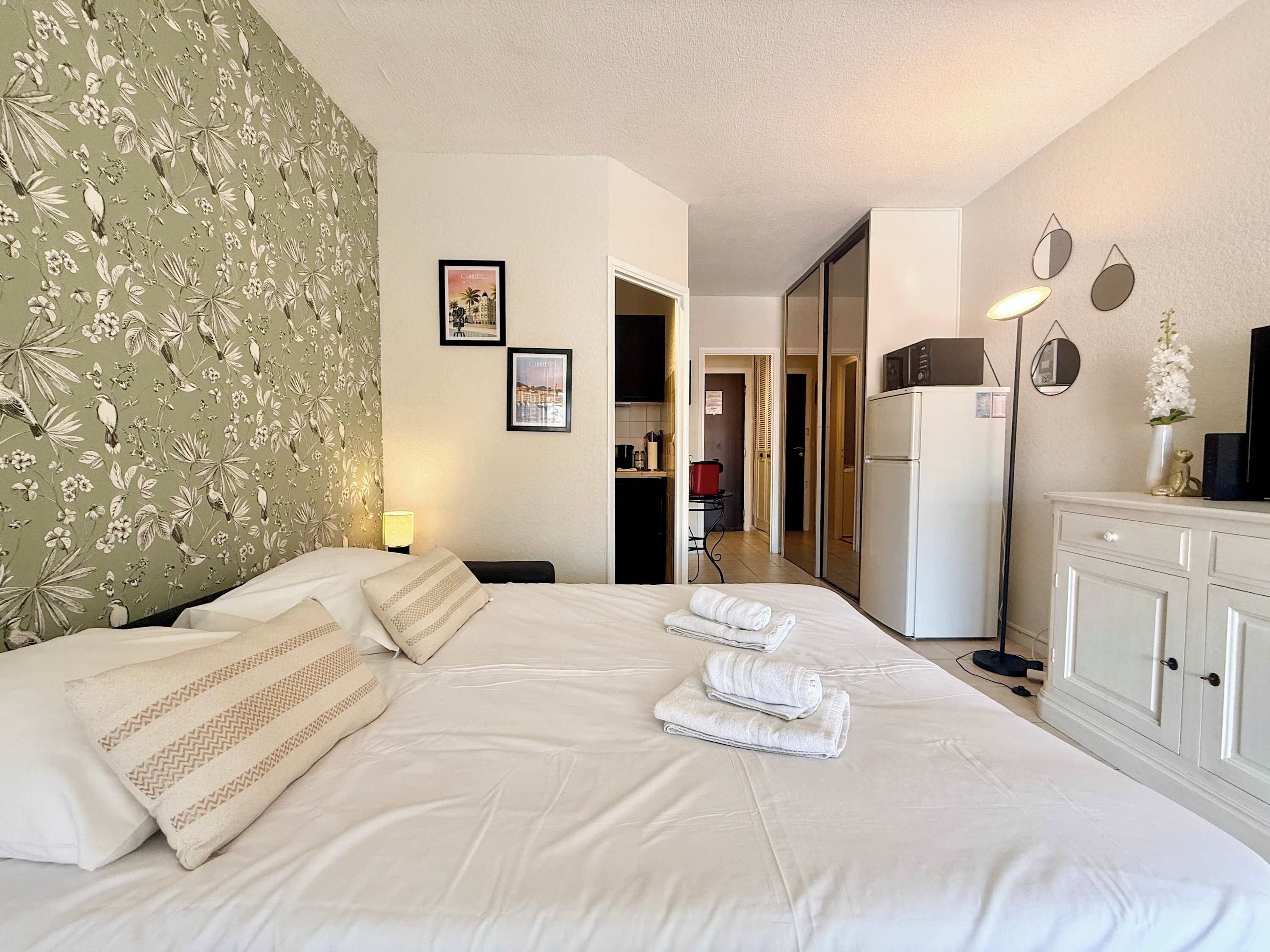 Quarto de hotel com cama, guarda-roupa, escrivaninha e espelho.