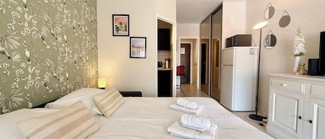 Hotellihuone, jossa on sänky, vaatekaappi, työpöytä ja peili.