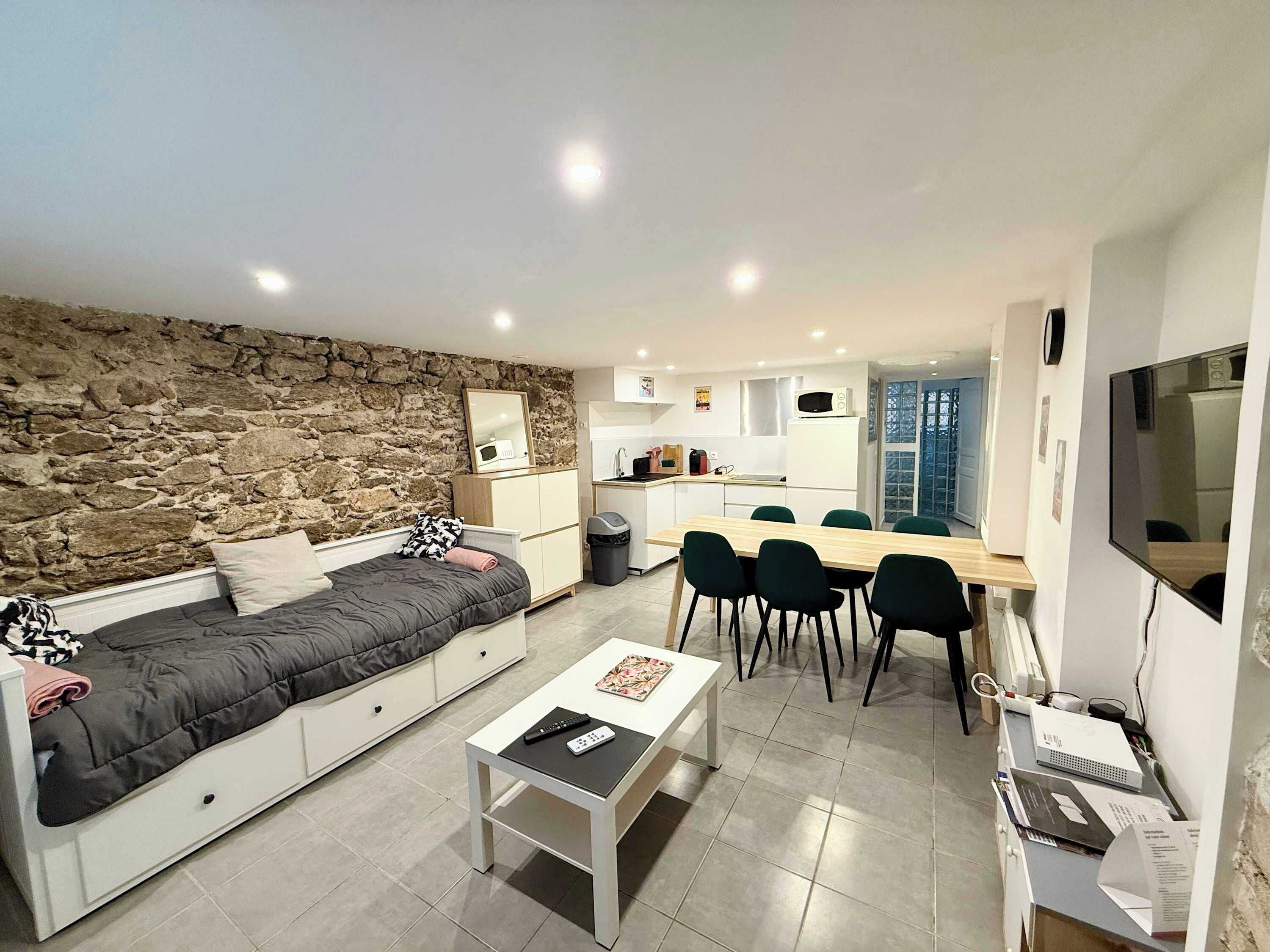 A modern living space with a stone wall, a sofa, a dining area, and a kitchen.
