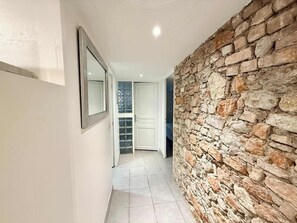Ein Korridor mit Steinwand, einer Tür mit Glasfeldern und einem gefliesten Boden.