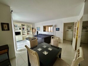 A modern living room with a sofa, a dining table with chairs, and a kitchen area in the background. - A007 - Appartement chic au coeur de Cannes (Cannes)