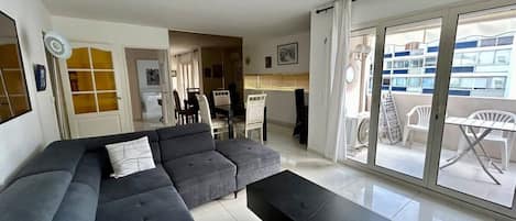 A modern living room with a sectional sofa, a coffee table, and a dining area with chairs and a table.