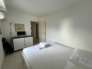 A hotel room with a bed, a desk with a computer, a chair, and a coat rack. - A007 - Appartement chic au coeur de Cannes (Cannes)