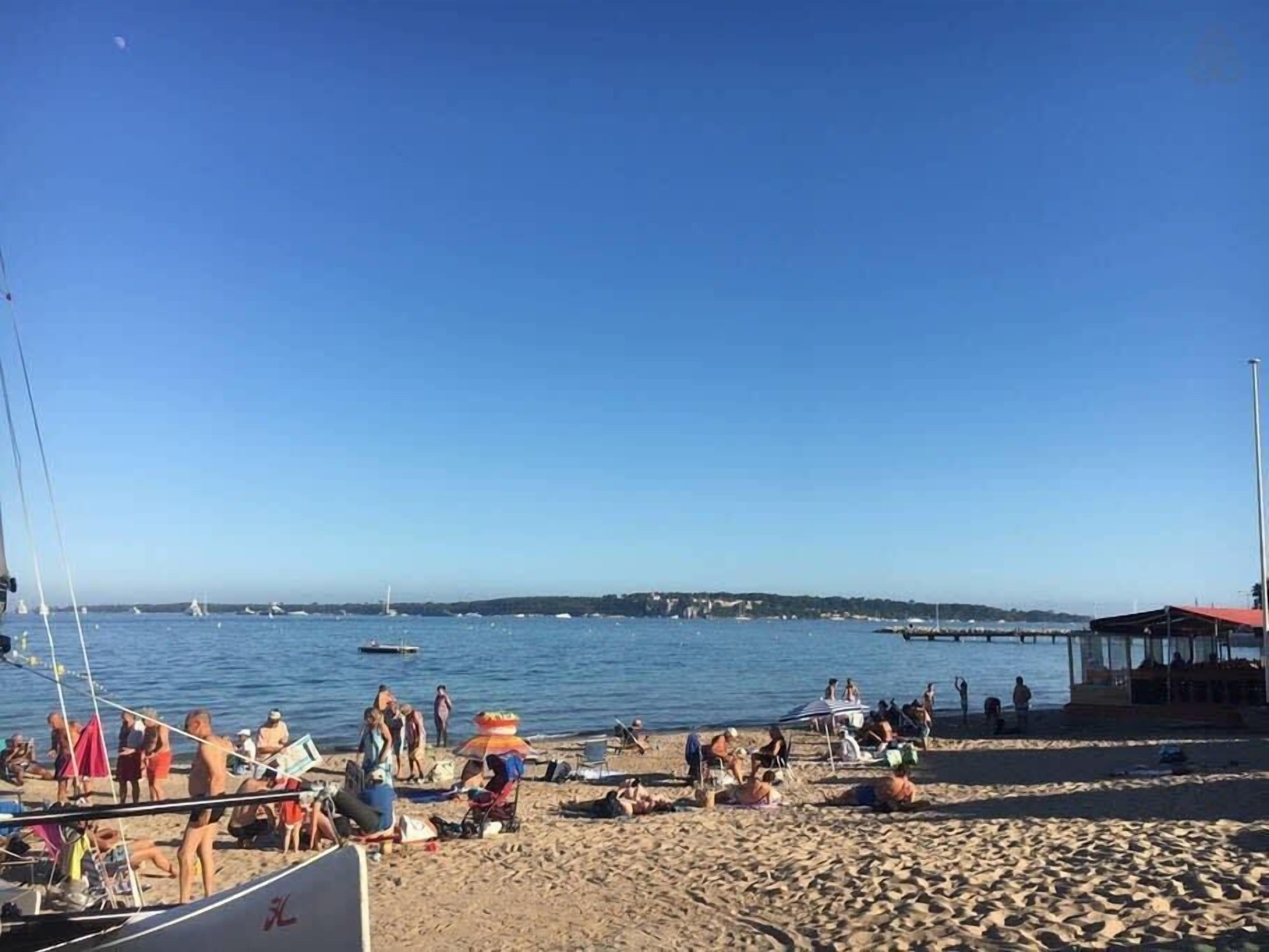 A beach with people, boats, and a pier.