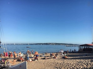 Ein Strand mit Menschen, Booten und einem Steg.