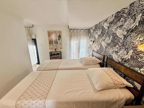 A hotel room with two beds, a poster on the wall, and a patterned wallpaper on one side. - A088 Élégant duplex avec terrasse, plages, centre (Cannes)