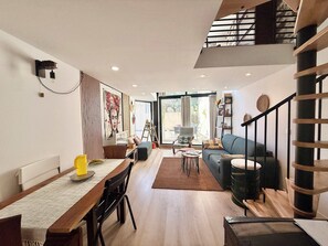 A modern living room with a dining area, a staircase, and a view of the outdoors. - A088 Élégant duplex avec terrasse, plages, centre (Cannes)