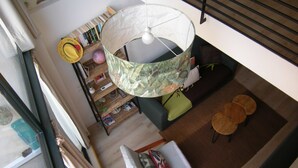 Ein Raum mit hohen Decken, einem großen, runden Tisch mit Muster, einer Hängelampe und einer Treppe.