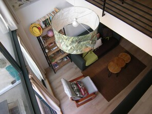 A high-ceiling room with a large, round, patterned table, a hanging light fixture, and a staircase. - A088 Élégant duplex avec terrasse, plages, centre (Cannes)