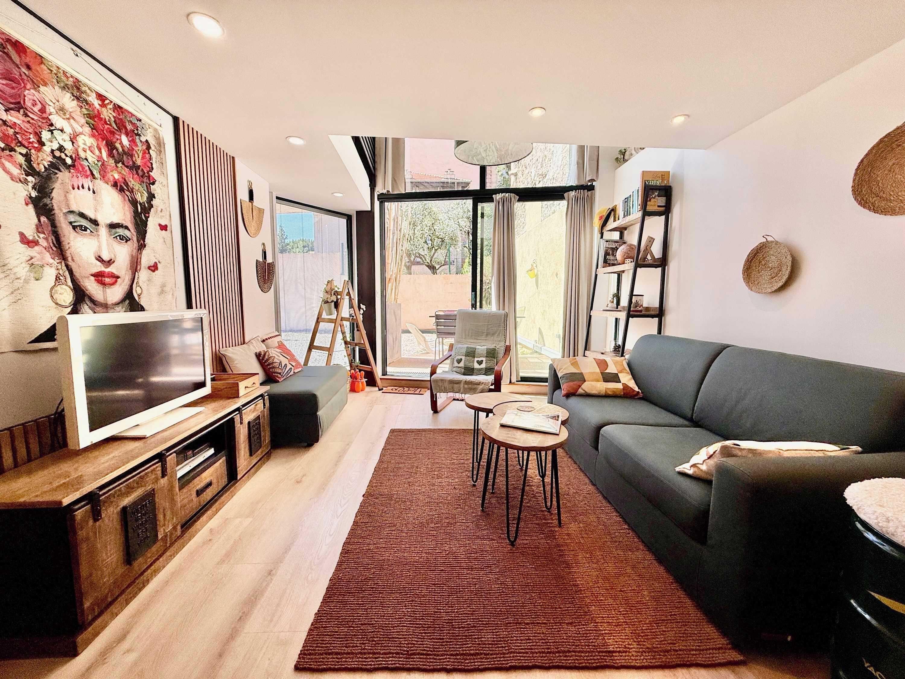 Ein modernes Wohnzimmer mit Fernseher, Sofa, Couchtisch und Kunstwerk an der Wand.