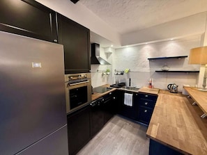 Eine moderne Küche mit einem Edelstahl-Kühlschrank, einem eingebauten Backofen und Holzarbeitsplatten.