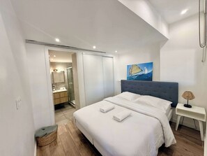 Ein modernes Schlafzimmer mit einem großen Bett, einem Nachttisch, einer Lampe und einem Bild an der Wand.