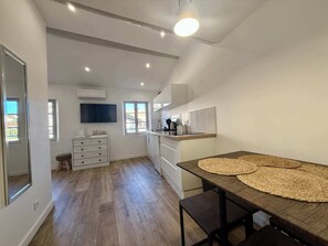 Une cuisine moderne avec des meubles blancs, une table à manger en bois et une grande fenêtre qui laisse entrer la lumière naturelle.