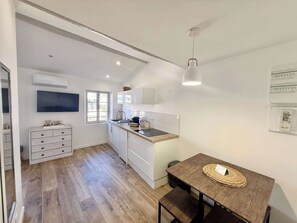 Eine kleine Küche mit Holztisch und Bank, einem eingebauten Backofen und einem Fenster.