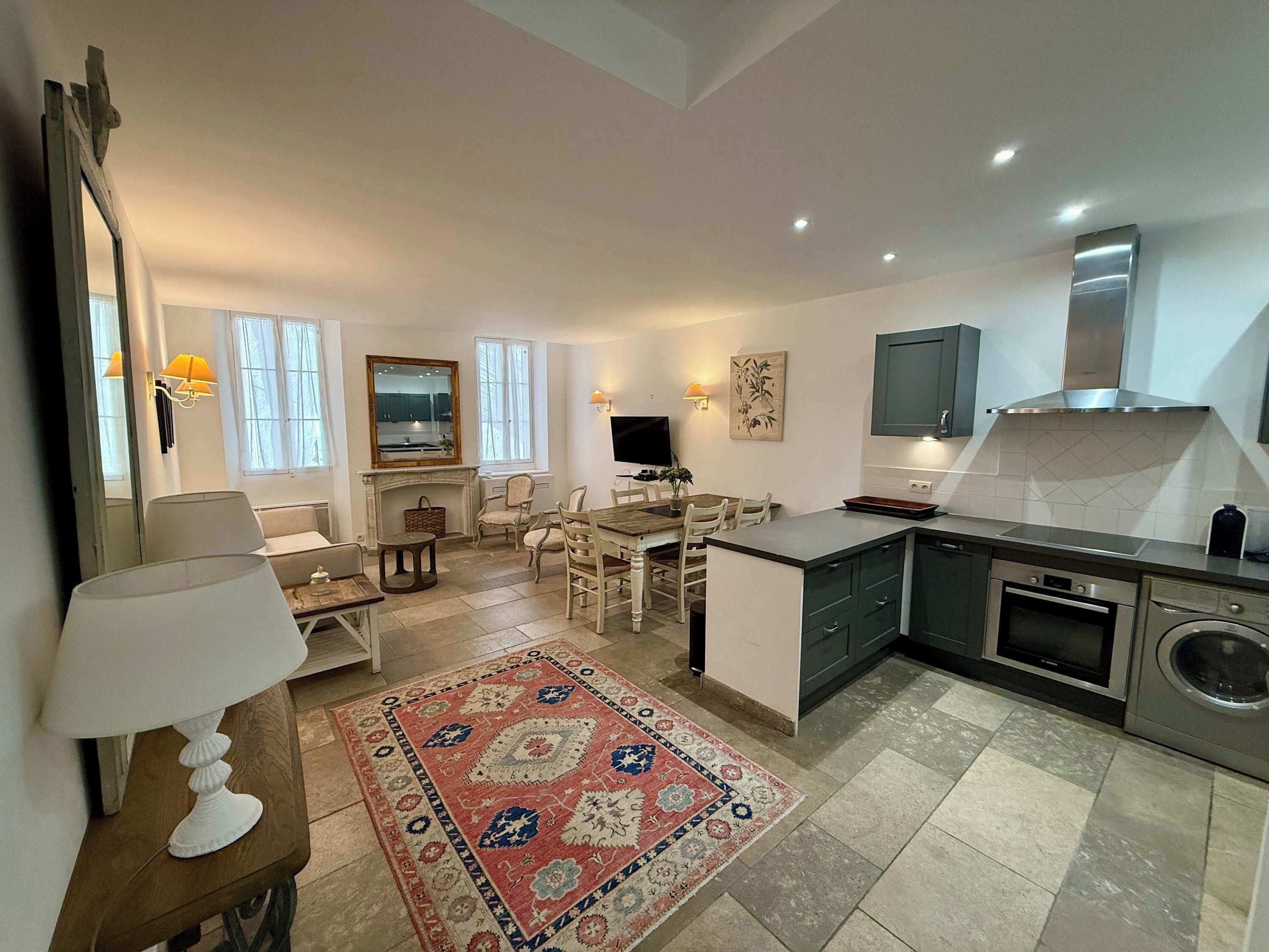 A modern kitchen with a dining area, a fireplace, and a large mirror.