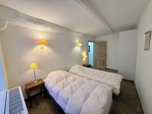 A hotel room with two beds, bedside lamps, a radiator, and a door leading to another room. - B003 Superbe 2 chambres centre Cannes (Cannes)