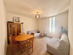 Ein gemütlicher Wohnraum mit Esstisch, Stühlen, einer Couch, einem kleinen Nachttisch und einer Lampe.