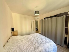 Ein Schlafzimmer mit einem Bett, einem Nachttisch, einer Hängelampe und einer Tür zu einem Badezimmer.
