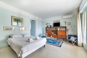 A bedroom with a bed, a wooden bookshelf, a blue chair, and a window with curtains. - A056 - Nice Studio Cannes centre with parking (Cannes)