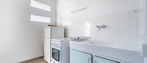 A compact kitchen with a refrigerator, oven, sink, and cabinets.