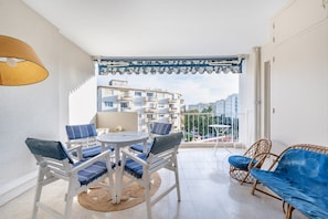 A balcony with a table and chairs, a wicker sofa, and a view of buildings. - A056 - Nice Studio Cannes centre with parking (Cannes)