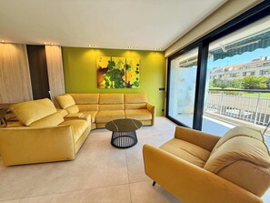 Ein modernes Wohnzimmer mit einer Eckcouch, einem runden Couchtisch und einem großen Fenster mit Blick auf die Stadt.