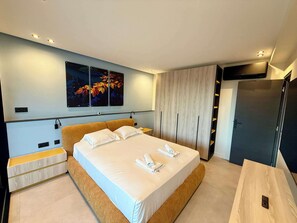 A modern bedroom with a large bed, a wooden headboard, a flat-screen TV, and a wardrobe. - B027 Magnifique 3 chambres parking, tout à pied (Cannes)