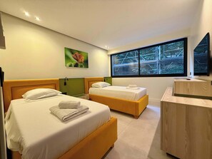 Une chambre d’hôtel moderne avec deux lits, une grande fenêtre, un tableau et un bureau en bois.