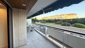 Ein Balkon mit Blick auf ein Gebäude, einem Tisch mit Stühlen und einer Brüstung.