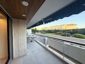 Ein Balkon mit Blick auf ein Gebäude, einem Tisch mit Stühlen und einer Brüstung.