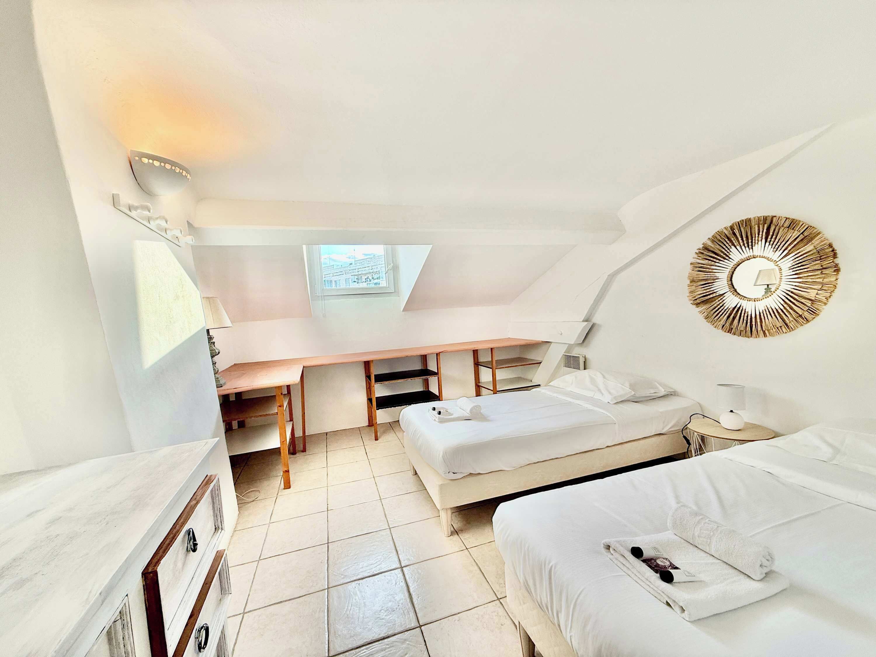 A compact, well-lit room with a bunk bed, a desk, and a small window.