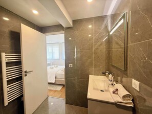 A modern bathroom with a large mirror, a white sink, and a towel rack. - B044 Studio moderne Croisette 100m (Cannes)