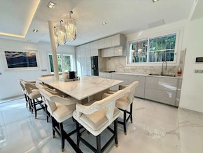 A modern kitchen with a marble countertop, a large island with chairs, and pendant lighting. - B077 Superbe villa avec piscine centre de Cannes (Cannes)