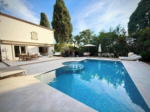 Ein rechteckiger Pool mit glasklarer, blauer Wasseroberfläche, umgeben von einer gepflasterten Liegefläche.