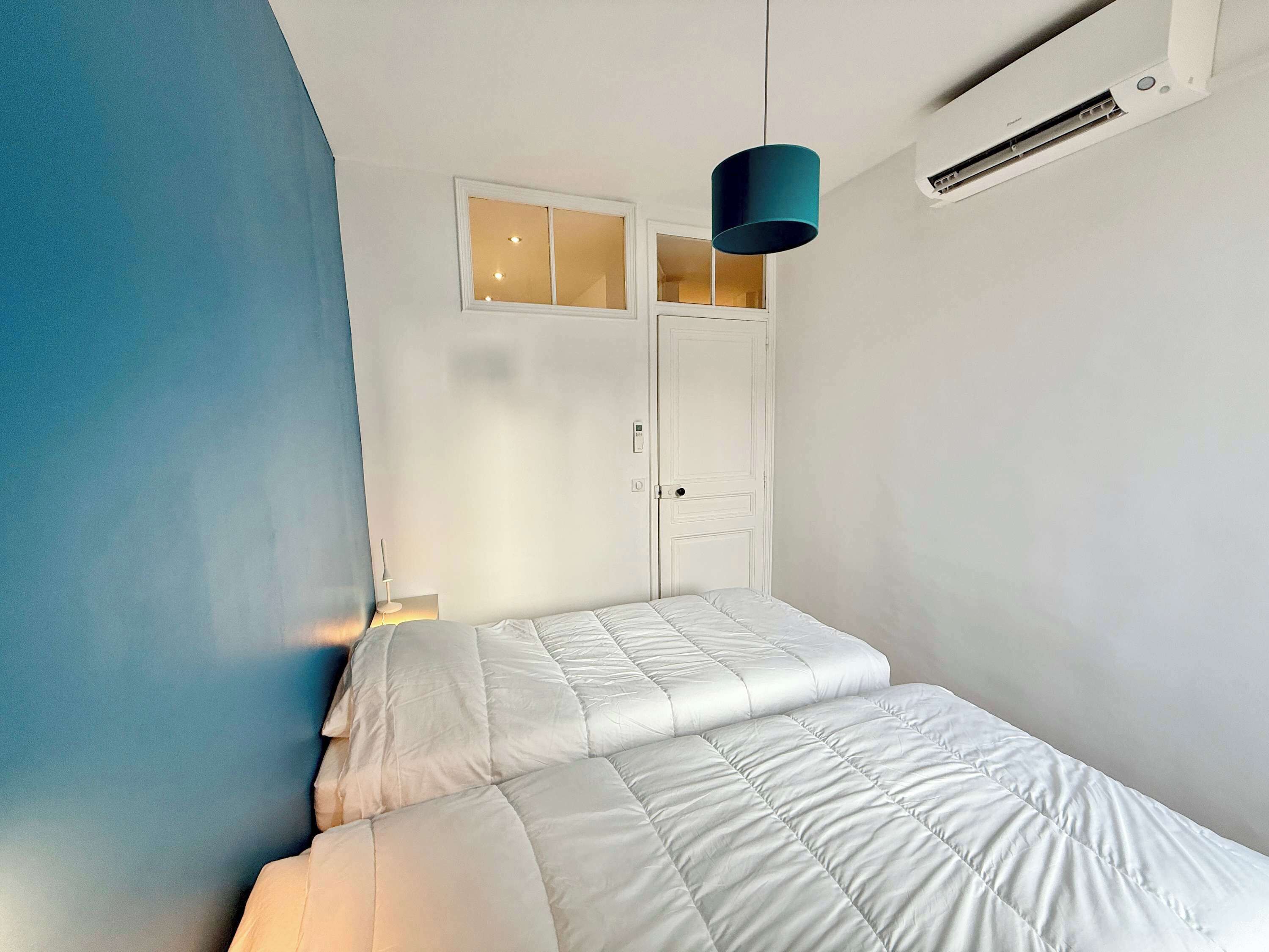 A bedroom with a bed, a window, and a door.