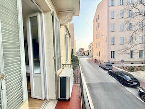 Eine Wohnstraße mit Balkon, einem parkenden Auto und einem Gebäude mit vielen Fenstern.