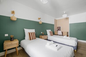 Hotellihuone, jossa on kaksi sänkyä, työpöytä ja tuoli.